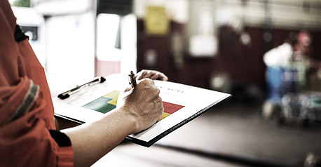 A manager is holding a pen and risk matrix form with factory workshop