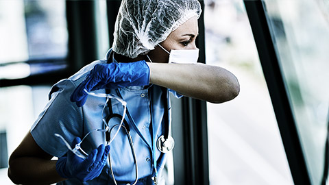 A nurse coughing while wearing PPE