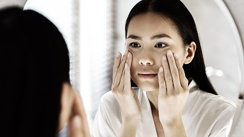 A person looking at their skin in the mirror