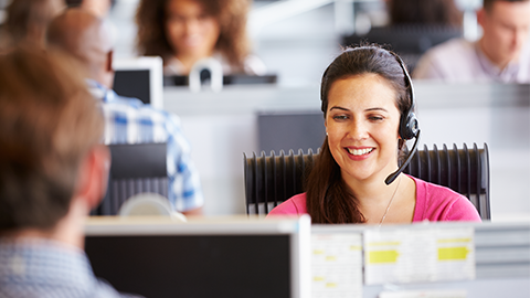 Young woman working in call centre, surrounded by colleagues