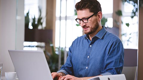 Confident young businessman working on laptop