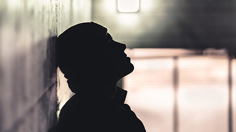 A person standing against a wall in a dark corridor