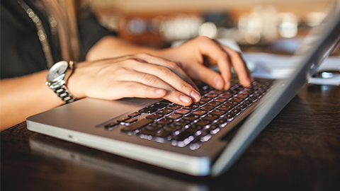 Hands of young business woman in cafe drinking coffee with laptop indoor