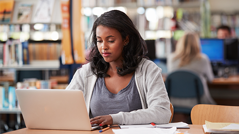 Mature Female Student Working On Laptop In College Library