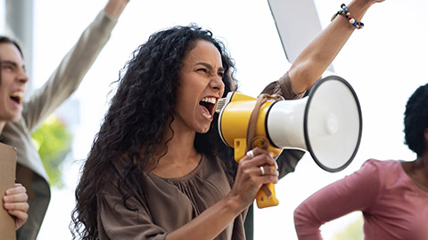 motivated young woman with loudspeaker leading international group of strikers