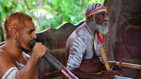 Australian Aboriginal men play Aboriginal music on didgeridoo and wooden instrument