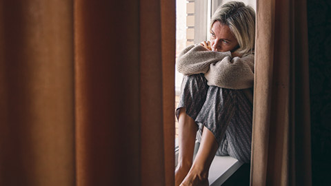 A person with mental health issues sitting on a window sill