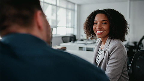 Young smiling beautiful businesswoman talking to a male colleague at workplace