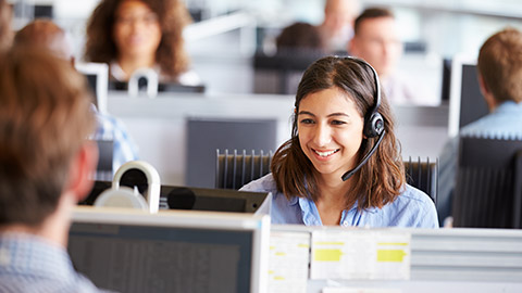 Young woman working in call centre, surrounded by colleagues