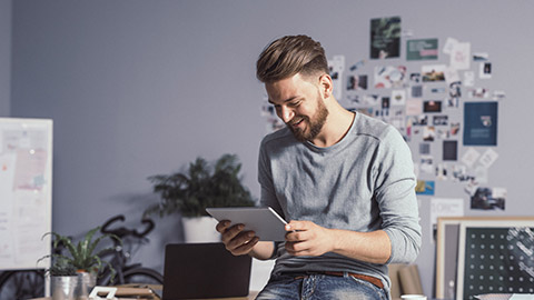 Young Handsome Designer Using Tablet and Smiling