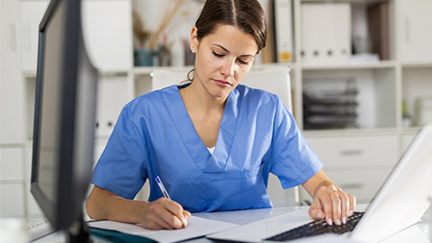 Positive female doctor working on laptop in clinic