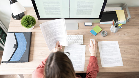 Top view of the workspace and office of a female translator working on a document and checking some references