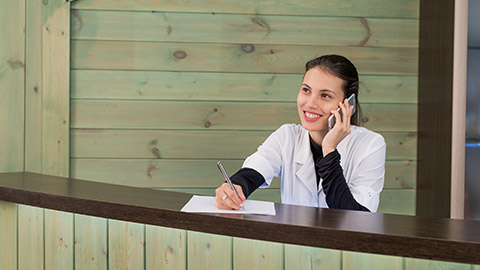 Portrait of female receptionist explaining form to patient in dentist clinic