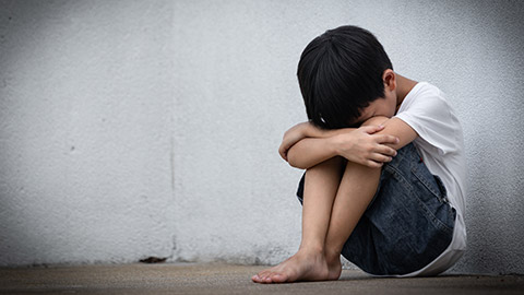 A young child sitting alone outdoors