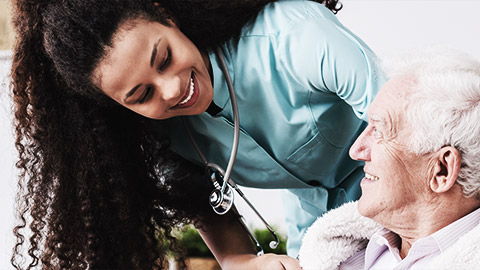 happy nurse with a stethoscope covering an elderly man