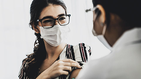 Young woman visits skillful doctor at hospital for vaccination . Covid 19 and coronavirus vaccination center service concept .