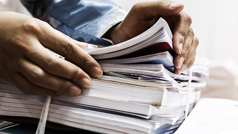 woman working in stacks of paperwork files for searching infomation