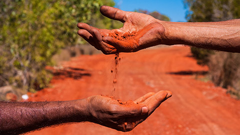 Indigenous people holding dirt