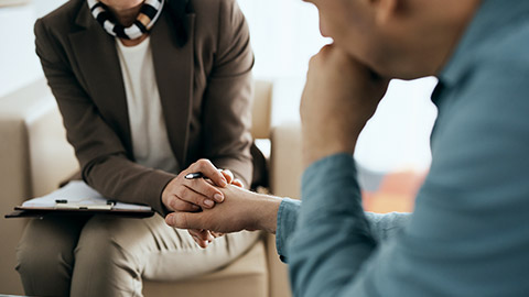 Close-up of caring therapist holding hands with her patient during mental health counseling