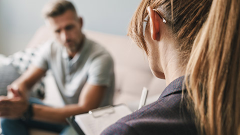 man having conversation with psychologist on therapy session in room