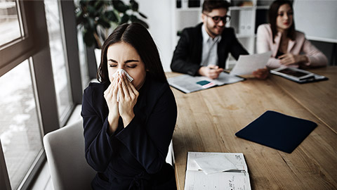 A person sneezing while in a meeting