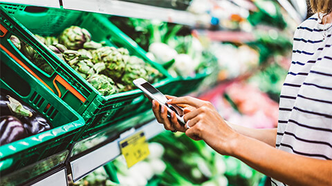 A person checking taking a moment to check their social media, while in the supermarket doing some grocery shopping