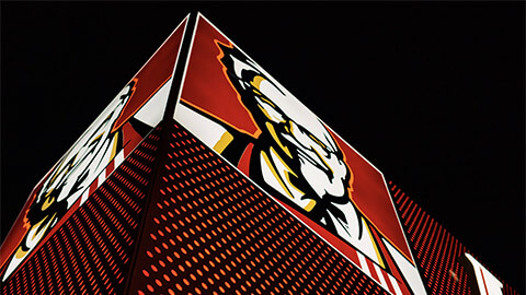 A very large KFC billboard from below, illuminated at night