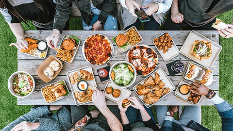 A group of friends sharing a meal outdoors, gathered around an eclectic mix of fastfood