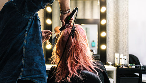 A hairdresser curling one of their clients long hair