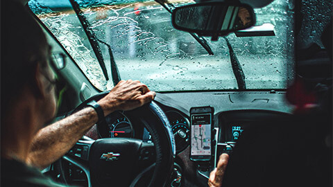 An Uber Driver delivering food to an Uber Eats user on a rainy afternoon