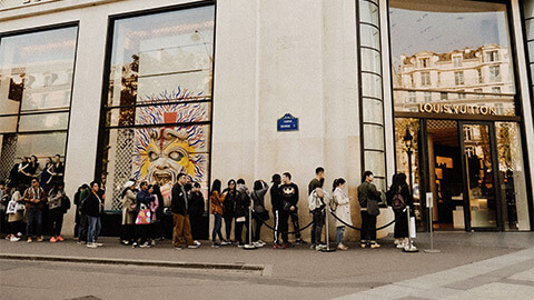 Shoppers waiting in line to enter Louis Vuitton