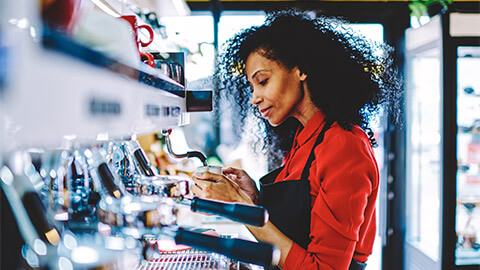 A barista frothing milk for a customer's coffee order