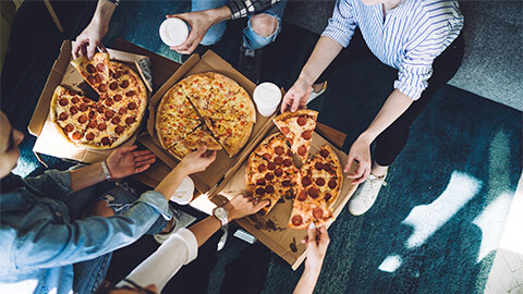 A group of friends sharing pizzas