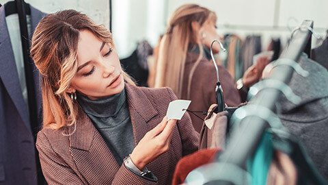 A young shopper looking at a garment and checking the price tag