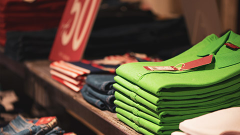 A clothing display in a store with a 50% off sign visible in the background