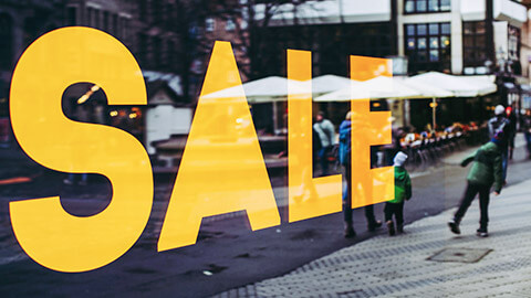 A close view of a sale sign in the window of a shop in a city