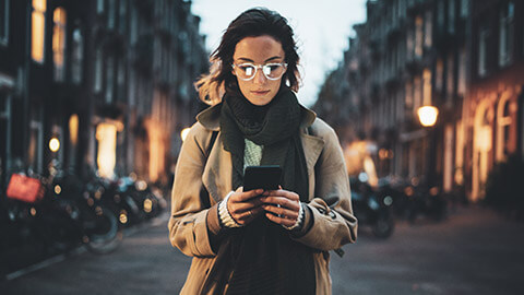 A young hipster checking her smartphone on a city street