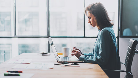 A business professional searching the internet on a laptop in a modern office space