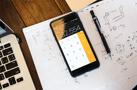 A calculator on an accountant's smartphone, on top of a notepad full of their recent equations and notes