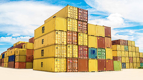 A large number of colourful shipping containers stacked on top of each other, full of business' inventory