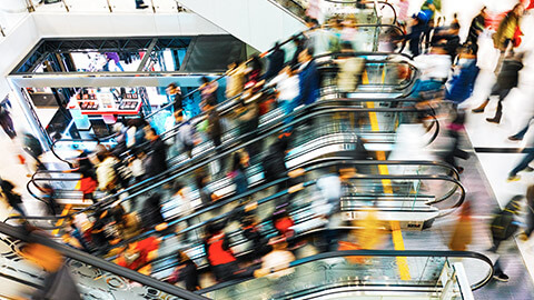 Interior of a busy store with lots of people using the escalators