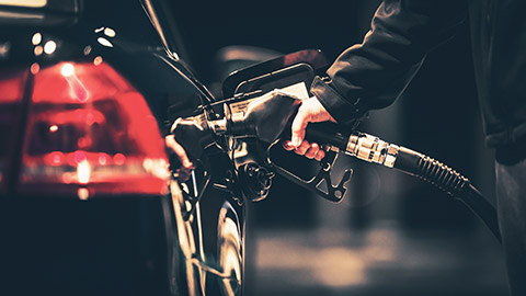 A close view of a person filling up their car at night