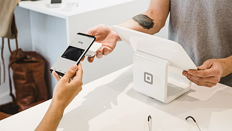 A customer paying for items using their smartphone on a Square Payment service belonging to a retailer