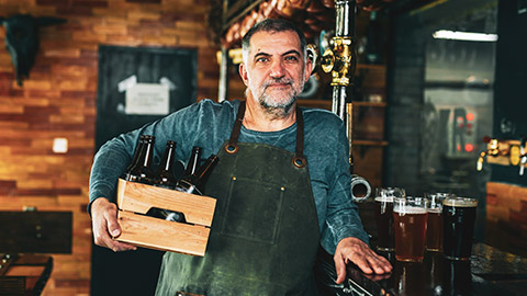 A mature entrepreneur standing in a bar with some of his product