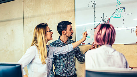 Three colleagues mapping out their organisation's life cycle curve on a whiteboard