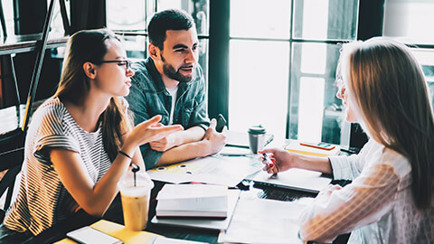 3 work colleagues discussing a marketing project in a modern office space