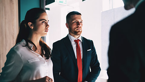 2 business colleagues with serious looks on their faces talking to their boss