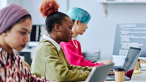 Diverse group of creative young people sitting in row while working in office focus on black young woman using laptop