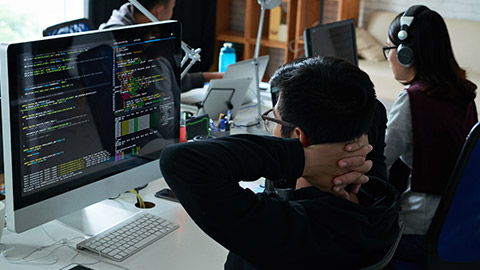 Pensive programmer looking at his code on computer screen