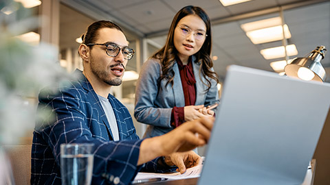 man and his female colleague using laptop while working in the office